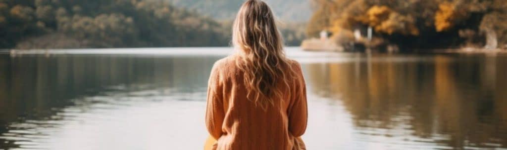 mujer mirando un lago en otoño