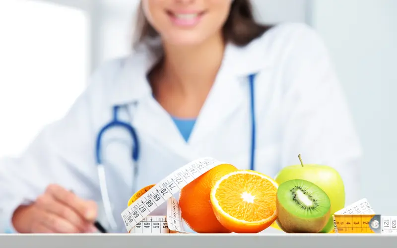 Nutricionista Adulto en su consulta presenta frutas y verduras para la dieta y plan nutricional de pacientes